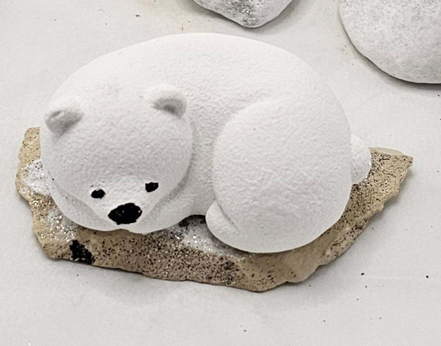 Kleine Eisbären auf Sandstein, teilweise mit Bäumchen.