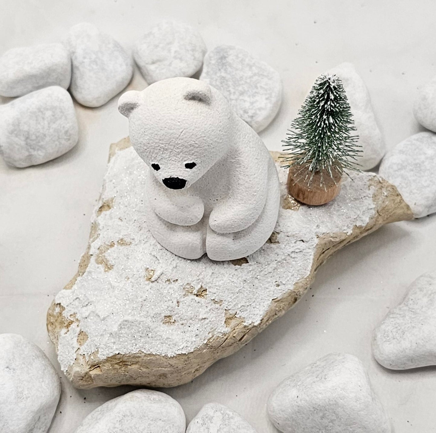 Kleine Eisbären auf Sandstein, teilweise mit Bäumchen.