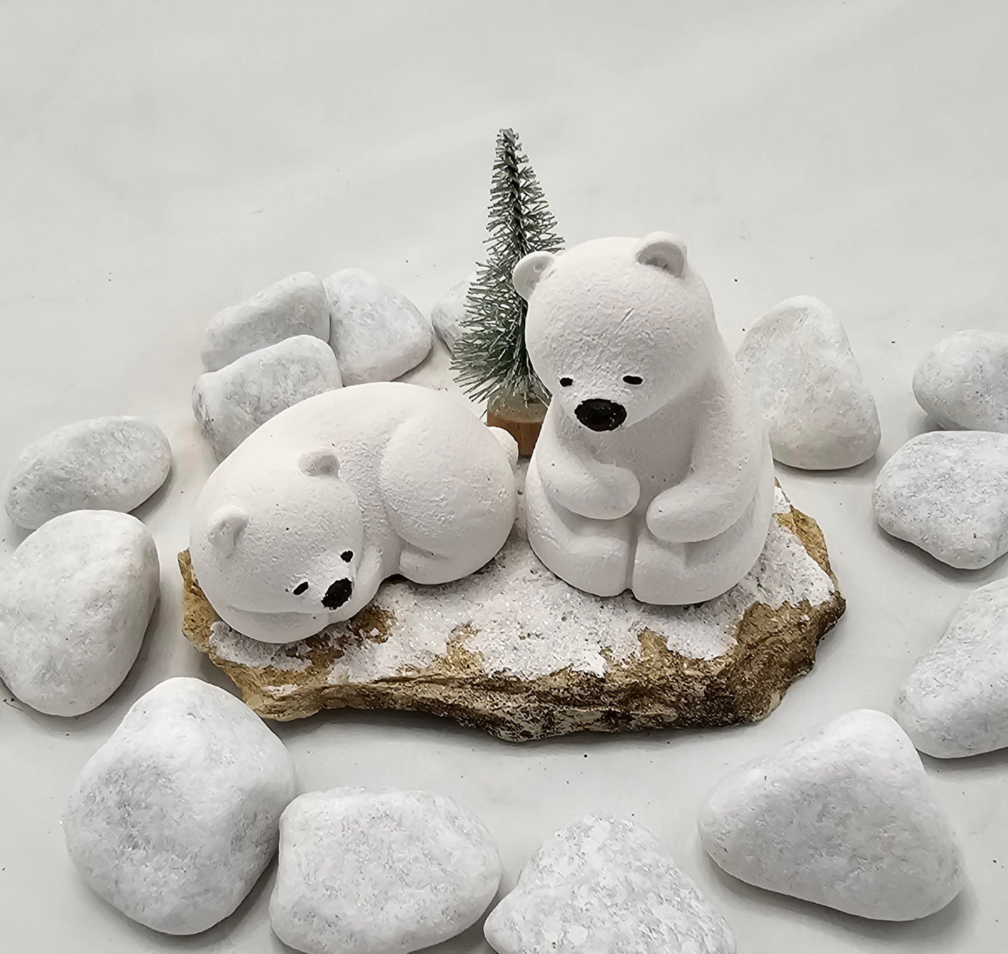 Kleine Eisbären auf Sandstein, teilweise mit Bäumchen.