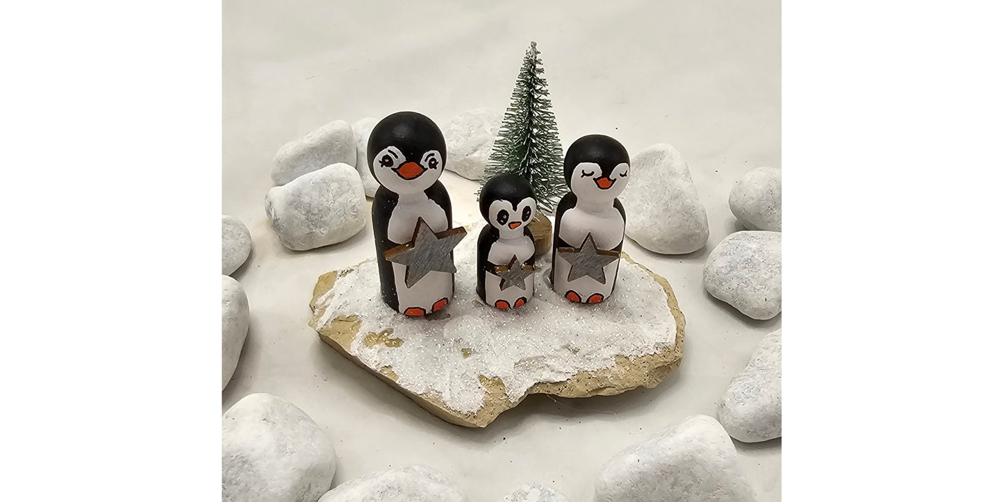 Pinguine Miniatur, gefertigt aus  kleinen Holzkegeln, auf Sandstein mit Bäumchen.