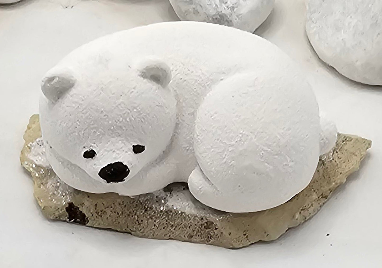 Kleine Eisbären auf Sandstein, teilweise mit Bäumchen.