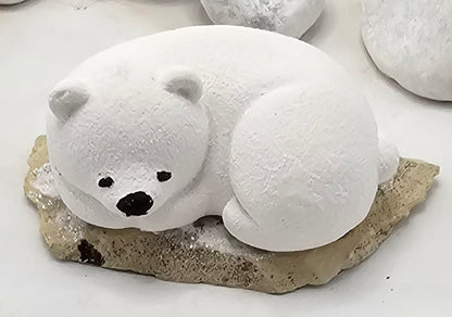 Kleine Eisbären auf Sandstein, teilweise mit Bäumchen.