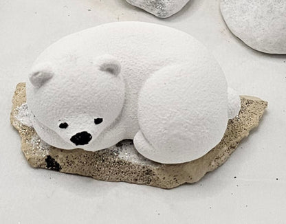 Kleine Eisbären auf Sandstein, teilweise mit Bäumchen.