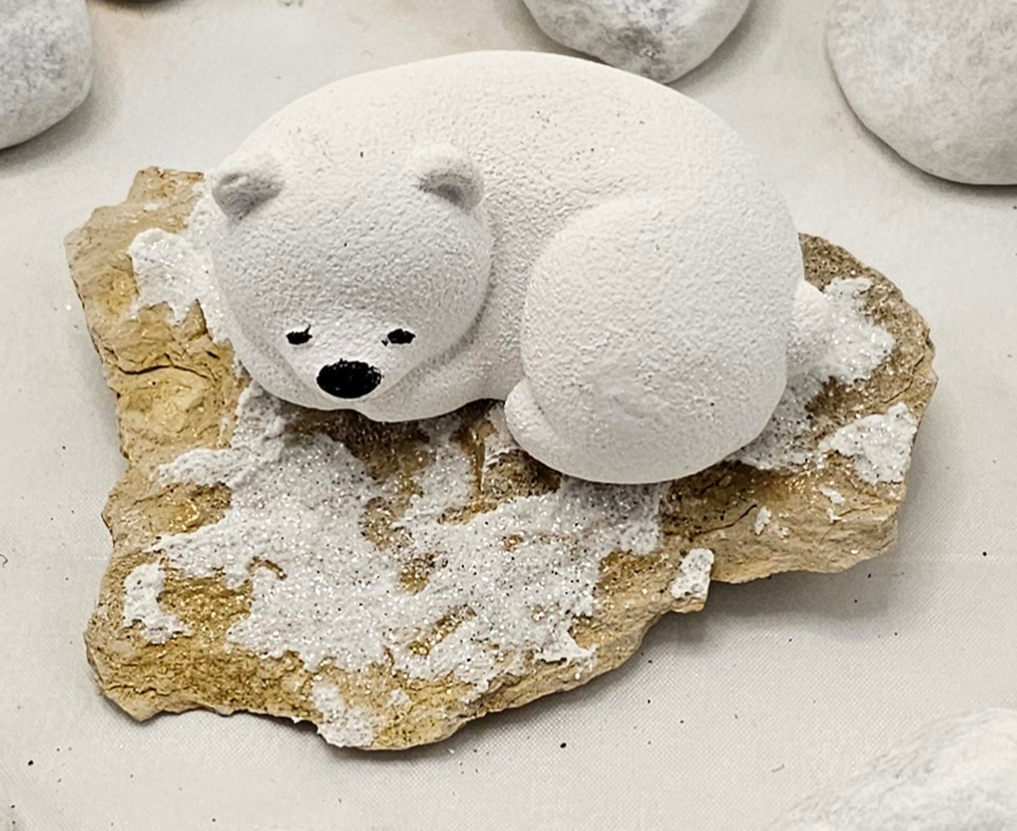 Kleine Eisbären auf Sandstein, teilweise mit Bäumchen.