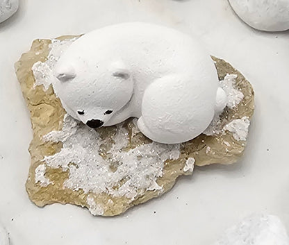 Kleine Eisbären auf Sandstein, teilweise mit Bäumchen.