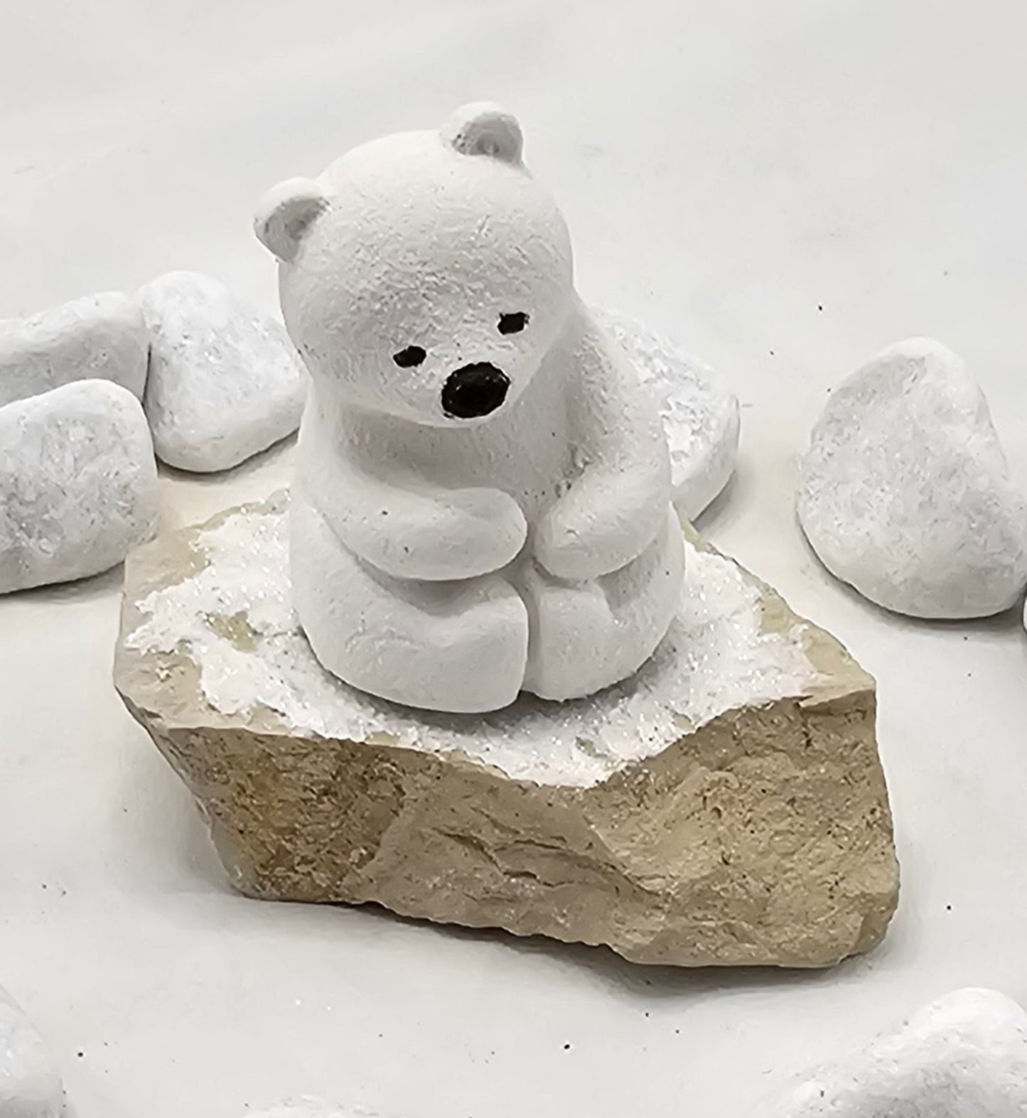 Kleine Eisbären auf Sandstein, teilweise mit Bäumchen.