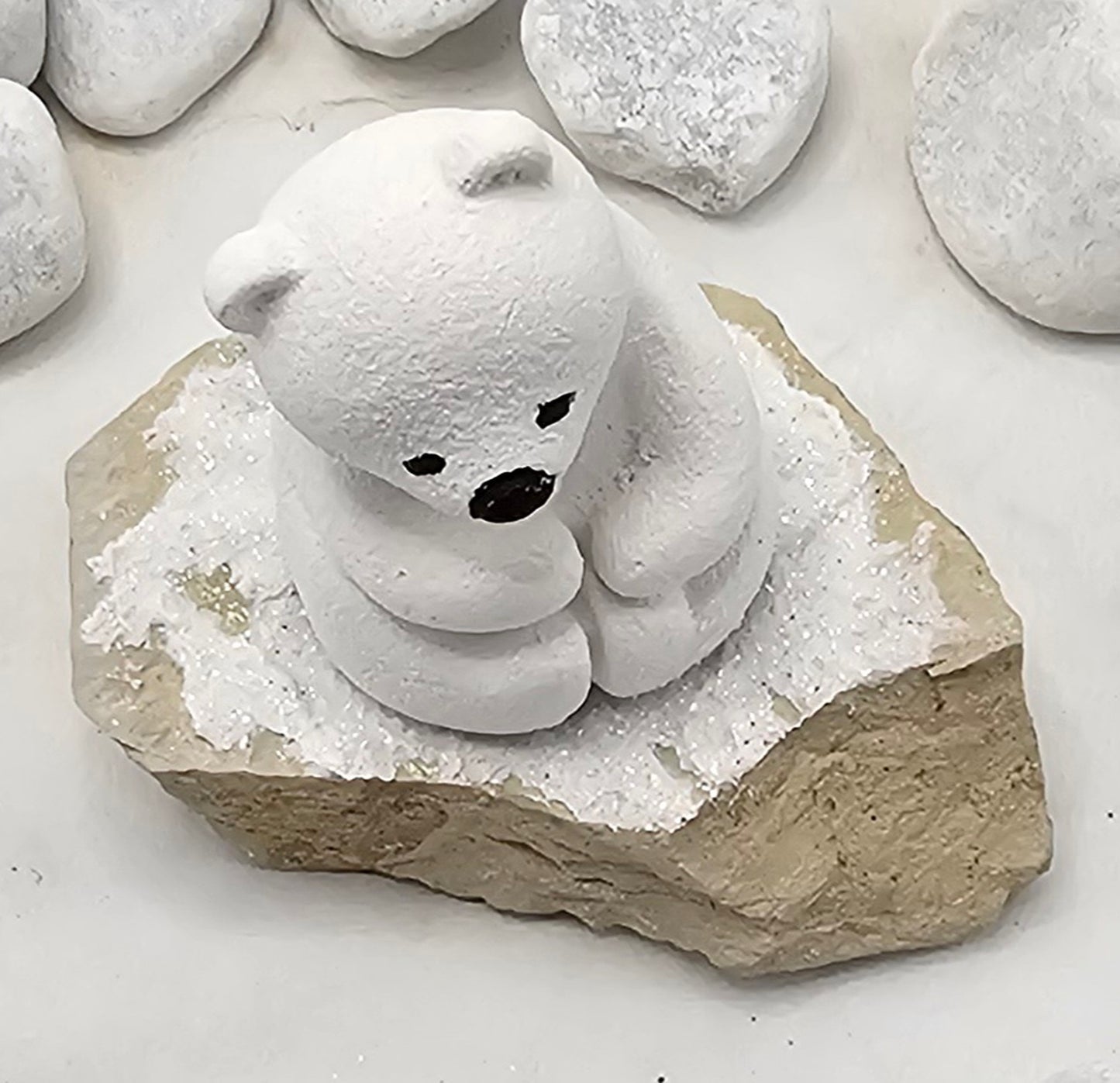 Kleine Eisbären auf Sandstein, teilweise mit Bäumchen.