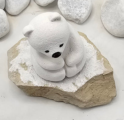 Kleine Eisbären auf Sandstein, teilweise mit Bäumchen.