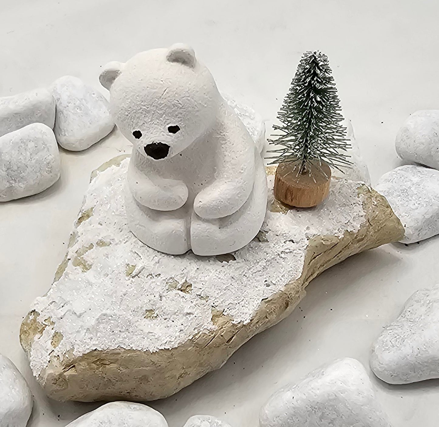 Kleine Eisbären auf Sandstein, teilweise mit Bäumchen.