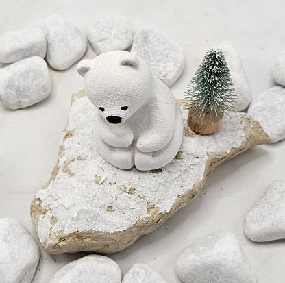 Kleine Eisbären auf Sandstein, teilweise mit Bäumchen.