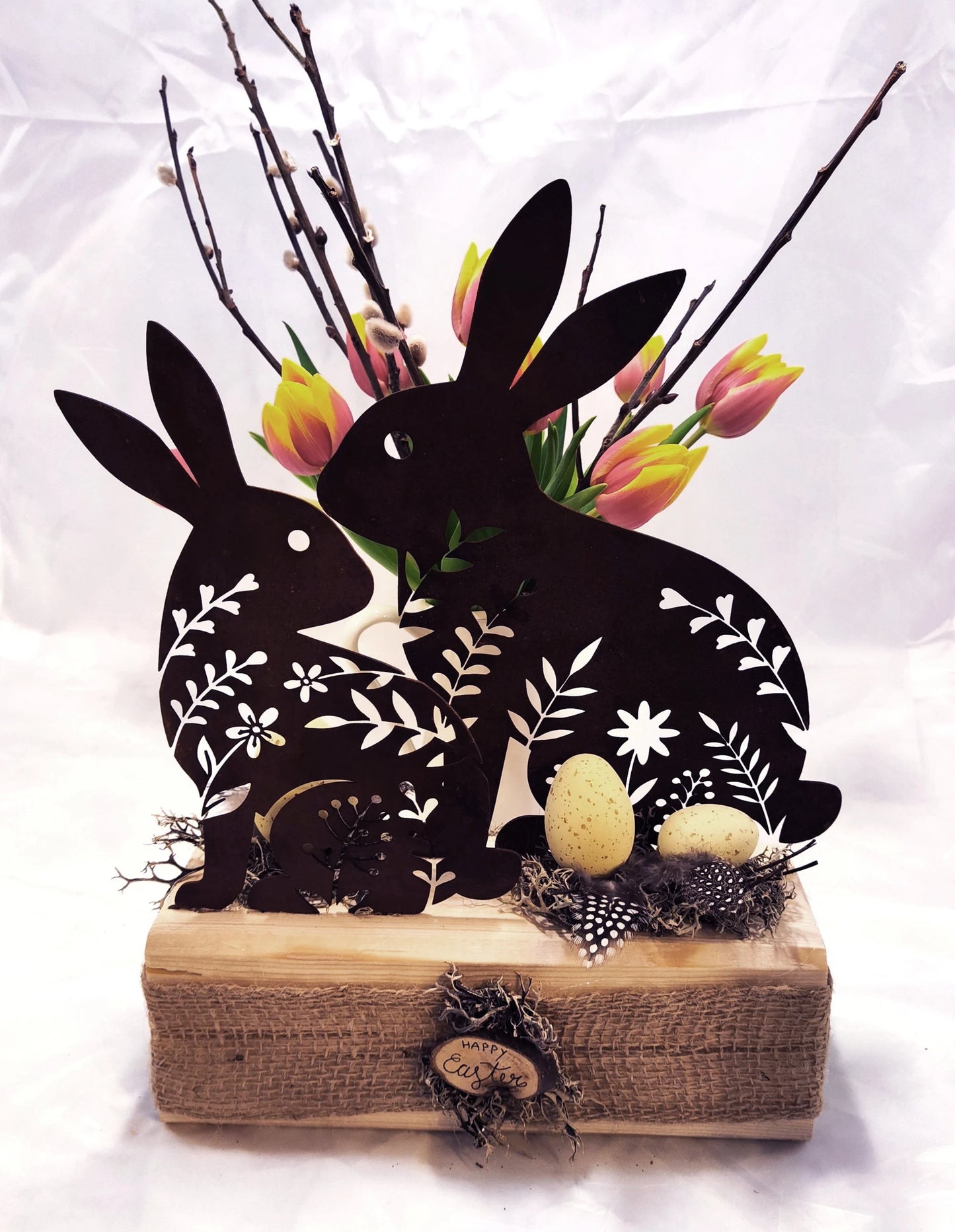 Hasen aus Stahl, in Rostoptik, österlich frühlingshaft auf Holz dekoriert