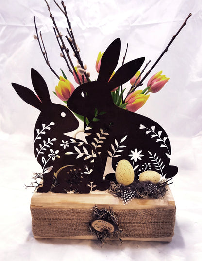 Hasen aus Stahl, in Rostoptik, österlich frühlingshaft auf Holz dekoriert