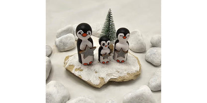 Pinguine Miniatur, gefertigt aus  kleinen Holzkegeln, auf Sandstein mit Bäumchen.