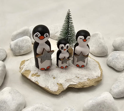 Pinguine Miniatur, gefertigt aus  kleinen Holzkegeln, auf Sandstein mit Bäumchen.