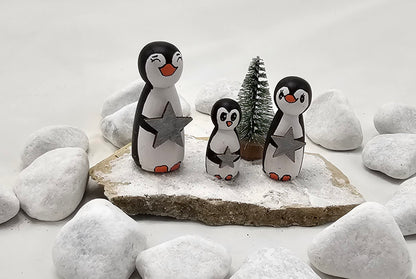 Pinguine Miniatur, gefertigt aus  kleinen Holzkegeln, auf Sandstein mit Bäumchen.