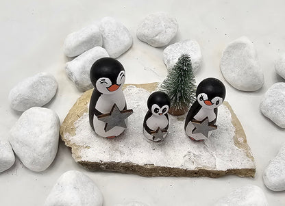 Pinguine Miniatur, gefertigt aus  kleinen Holzkegeln, auf Sandstein mit Bäumchen.